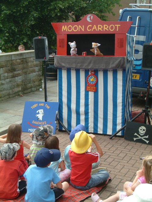 Children watching a Moon Carrot puppet show featuring a Rabbit and a Fox