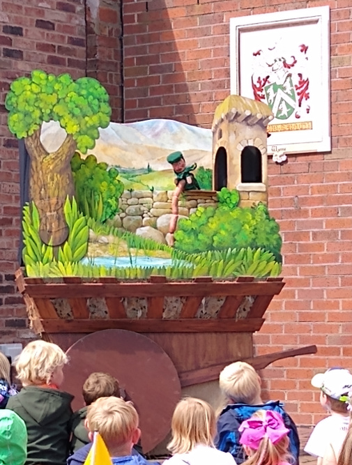 Moon Carrot's  Medieval Puppet Show performed from a cart style booth with audience watching